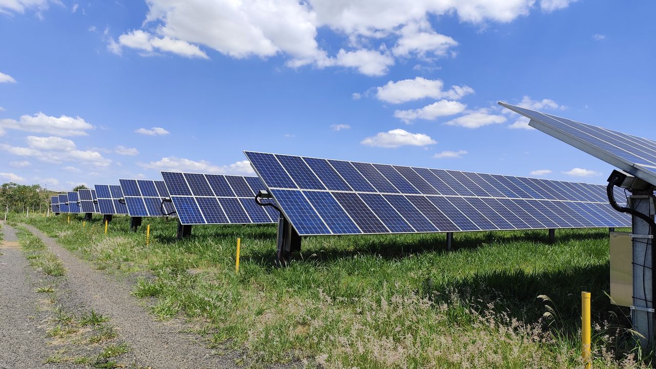 Solar panel array in a field under a bright blue sky in Uberlândia, Brazil. Renewable energy.